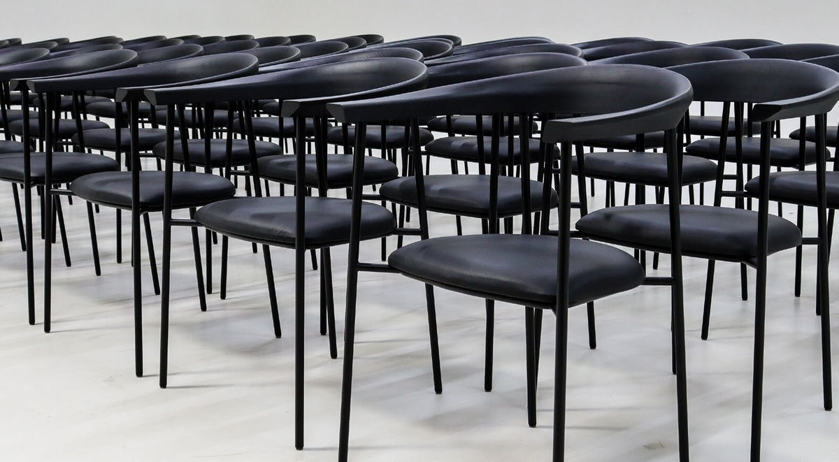 NUNC Nauvik dining chair, rows of black chairs in a hospitality setting